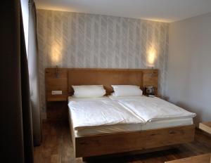Schlafzimmer mit einem Bett mit weißer Bettwäsche und Kissen in der Unterkunft Gasthof Vossbur in Toppenstedt
