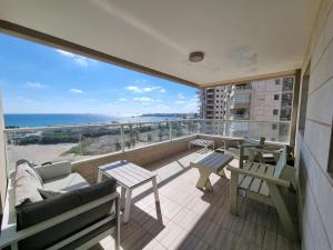 Un balcón con sillas y mesas y vistas al océano. en 7th Floor, en Acre