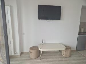 Dieses weiße Zimmer verfügt über einen Tisch und einen TV an der Wand. in der Unterkunft Studio Joy2Sea in Mamaia Nord – Năvodari
