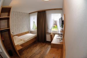 ein kleines Schlafzimmer mit einem Bett und zwei Fenstern in der Unterkunft Gasthof Vossbur in Toppenstedt