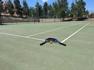 a tennis racket and ball on a tennis court at Quite & relaxing private apartment for 2-6 pers - Golf & Pool resort - Murcia in Murcia