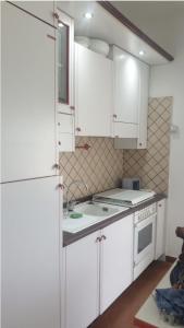 a kitchen with white cabinets and a white refrigerator at Casa Vacanze Don Sebastiano in Letojanni