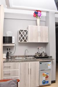 a kitchen with white cabinets and a sink at Cozy Apartment Entebbe in Wakiso