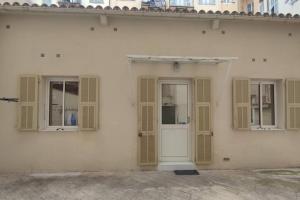 un edificio blanco con ventanas con persianas y una puerta blanca en Maison de ville port de Nice, en Niza