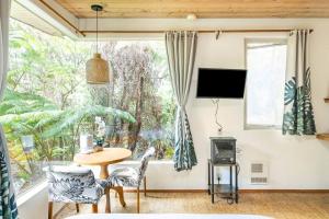 a living room with a table and chairs and a large window at Pahoehoe- Hale Kumu La'au at Volcano in Volcano
