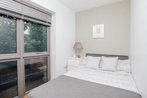 a white bedroom with a bed and a window at Peels yard - Central Henley in Henley on Thames