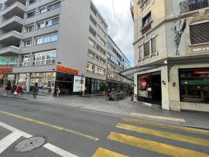 una via cittadina con edifici e persone che camminano sul marciapiede di 85m2 au centre-ville à 2 pas du Jet d'eau a Ginevra