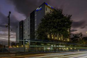 un edificio alto con un autobús delante de él en City Express Plus by Marriott Bogota Aeropuerto en Bogotá