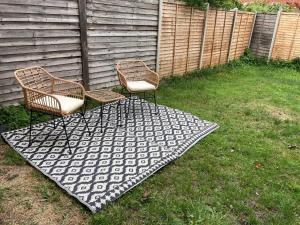 two chairs and a rug in a yard at Chessington Home Stay , 3 Bed 6 Guests Free Parking Near M25 JCT9, Chessington world of Adv Resort, Kingston, Epsom, Great for Families & Groups in Chessington