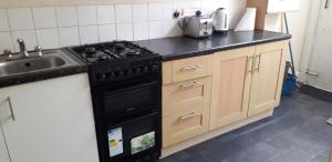 a kitchen with a black stove and a sink at Bird Song Guest House Old Trafford in Manchester