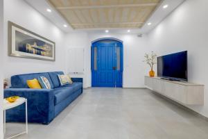 a living room with a blue couch and a tv at Kapitali 33A in Valletta