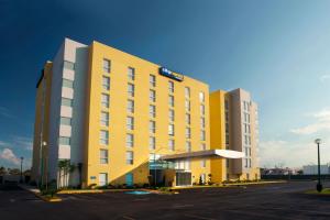 a yellow hotel with a parking lot in a parking lot at City Express by Marriott Aguascalientes Sur in Aguascalientes