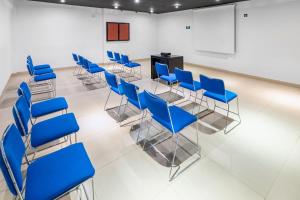 une salle de conférence avec des chaises bleues et un podium dans l'établissement City Express Junior by Marriott Veracruz Aeropuerto, à Veracruz