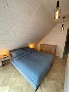 ein Schlafzimmer mit einem blauen Bett im Dachgeschoss in der Unterkunft Domki AS in Radawa