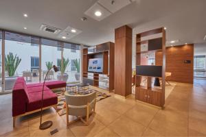 uma sala de estar com um sofá roxo e uma televisão em City Express Plus by Marriott Insurgentes Sur em Cidade do México