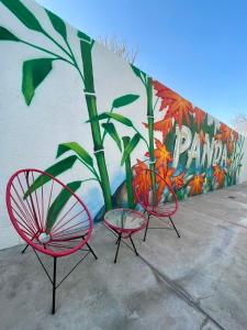 two red chairs and a plant in front of a wall at Panda Hostel Mendoza in Mendoza