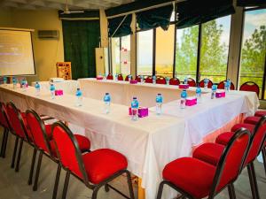 a long table with white table cloths and red chairs at Rock City Resort in Mingora