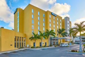 a yellow building with palm trees in front of a parking lot at City Express by Marriott Tampico in Tampico