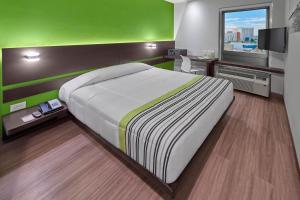 a bedroom with a large bed and a green wall at City Express Junior by Marriott Juarez Consulado in Ciudad Juárez