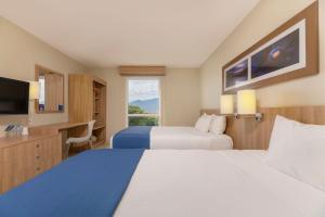 a hotel room with two beds and a flat screen tv at City Express by Marriott San José Costa Rica in San José