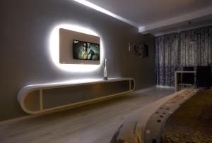 Cette chambre comprend un lit et une télévision murale. dans l'établissement Apartament Perla Falezei, à Galaţi