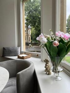 a vase of flowers on a table next to a window at Sophia's Cwtch in Cardiff