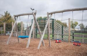 a playground with a swing set in a park at Kingfisher Quay Lodge in Clacton-on-Sea