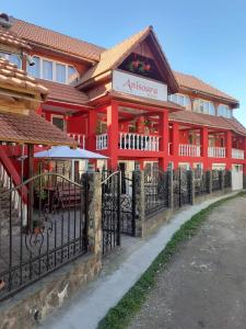 a red building with a fence in front of it at Pensiunea Anisoara in Chişcău