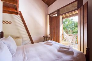 um quarto com uma cama branca e uma janela em Casa Amaargi Picinguaba em Picinguaba