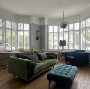 a living room with a green couch and a chair at Glenesk No 1 , Woodhall Spa in Lincolnshire