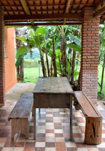 une table en bois et des bancs sur une terrasse dans l'établissement Casa do Alecrim, à São Roque de Minas