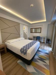 a bedroom with a large white bed and a desk at Grau Business Hotel in Piura