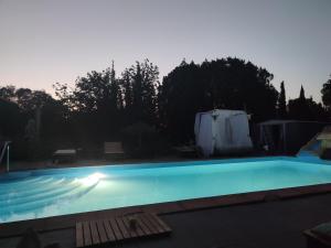 uma piscina à noite com as luzes acesas em Mobilhomes vintage dans ecolieux en cours camping a la ferme em Ponteilla