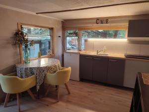 a kitchen with a table and chairs and a sink at Mobilhomes vintage dans ecolieux en cours camping a la ferme in Ponteilla