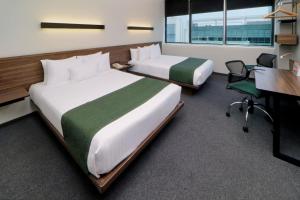 a hotel room with two beds and a desk and a desk at City Express Suites by Marriott Santa Fe in Mexico City