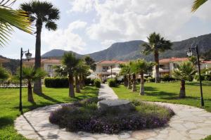 a walkway through a park with palm trees and houses at The One Club Hotel in Sarigerme