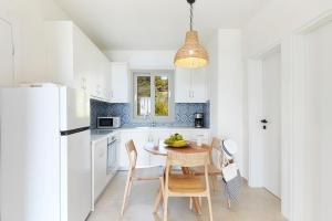 a kitchen with white cabinets and a table and chairs at Skiathos Ammos Luxury Apartments in Skiathos Town