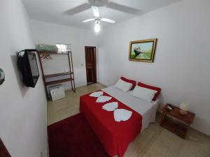um quarto com uma cama com lençóis vermelhos e almofadas brancas em Pousada toca do cambu em Angra dos Reis