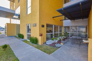 een geel gebouw met een patio met tafels en planten bij City Express by Marriott Monterrey Lindavista in Monterrey