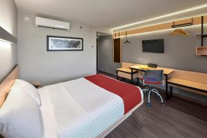 a hotel room with a bed and a desk and a table at City Express by Marriott Monterrey Lindavista in Monterrey +30 photos