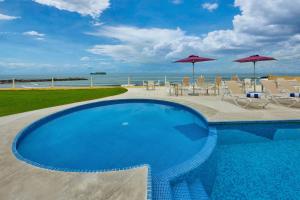 a swimming pool with tables and chairs and umbrellas at City Express by Marriott Veracruz in Veracruz