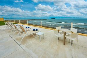 un patio con sillas, mesas y el océano en City Express by Marriott Veracruz en Veracruz