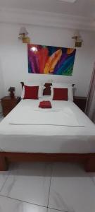 um quarto com uma grande cama branca com almofadas vermelhas em Damech Apparts em Iaundé