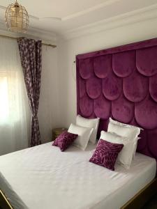 a bedroom with a purple headboard and a bed with pillows at Damech Apparts in Yaoundé