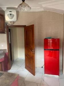 a kitchen with a red refrigerator next to a wall at Damech Apparts in Yaoundé