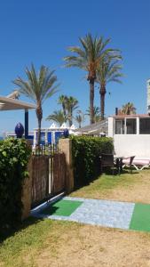 a garden with palm trees and a house with a gate at Casita Beach Front in Torrox Costa