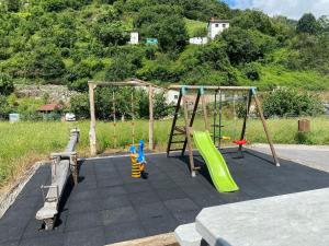 a playground with two slides and a swing set at Apartamentos El Campal in Felechosa