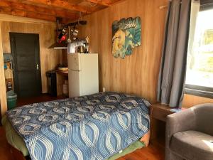 a room with a bed and a refrigerator and a chair at El banzai in Punta Del Diablo