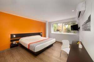 a bedroom with a bed and a desk and a window at City Express Junior by Marriott CDMX Sullivan in Mexico City