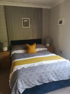 a bedroom with a large bed with a yellow pillow at Y Cuddfan Gower in Swansea